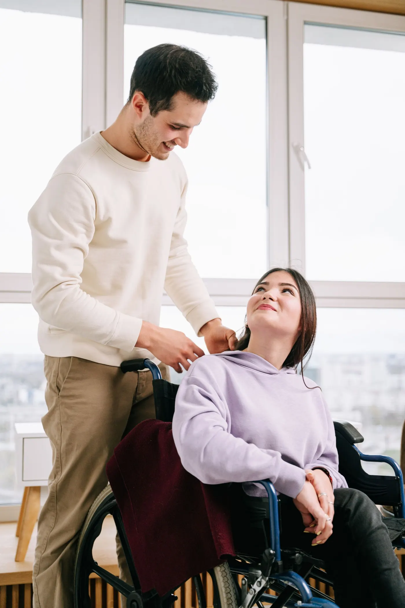A woman pushing a man in a wheelchair on a sunny day
